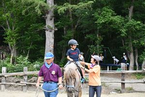 馬の背中に乗って笑顔を見せる参加児童